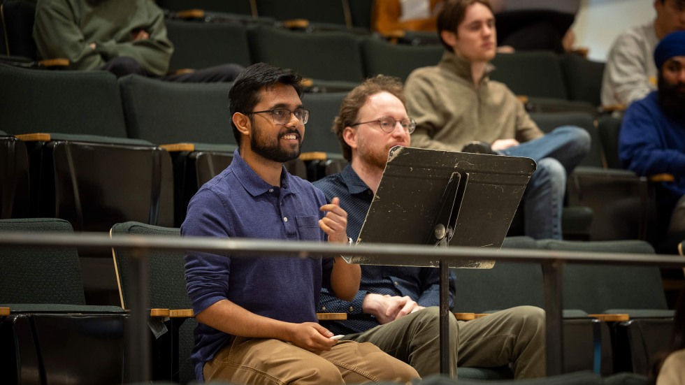 student and professor listen to musicians