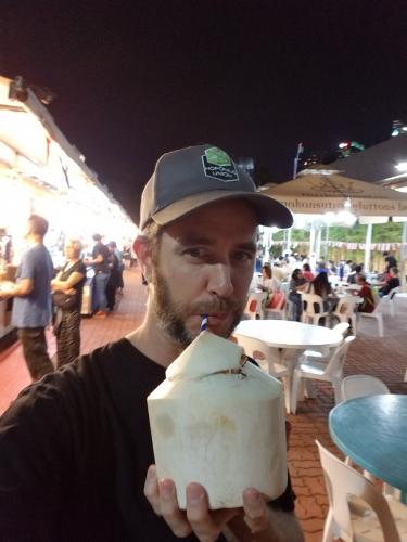 Dave drinking out of a fresh coconut in Singapore
