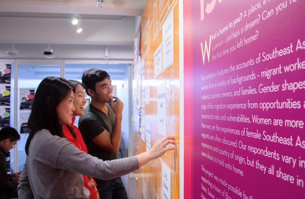 Three YSEALI fellows study a bright pink and yellow wall display at the Science Center at Brown University.