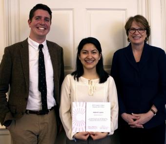 Idalmis Lopez stands holding her certificate. On her left is Andrew McQuaide, Senior Director at Perspectives Corporation, and on her right is Brown University President Christina Paxson.