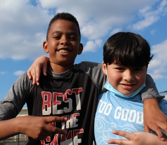 Photo of two young boys posing with their arms around each other's shoulders. 
