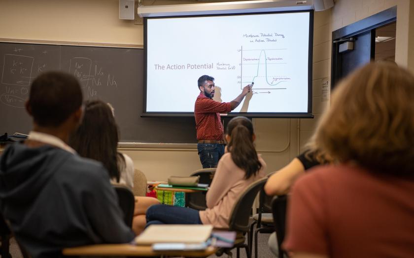 male student pointing at slide