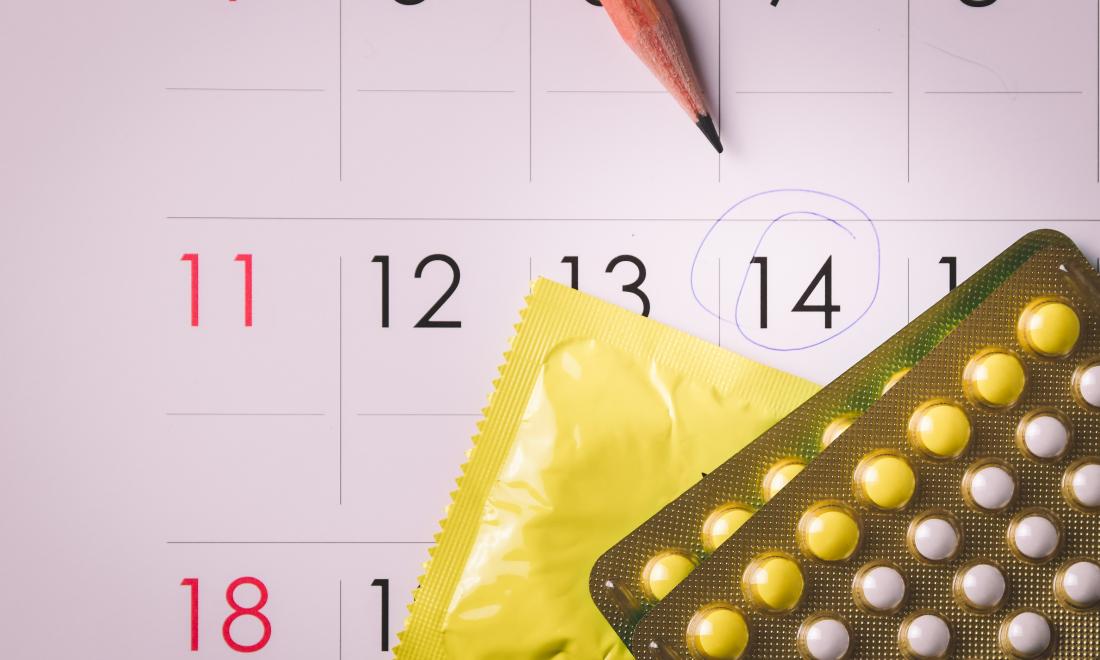 calendar with the 14th circled and packs of oral contraceptives