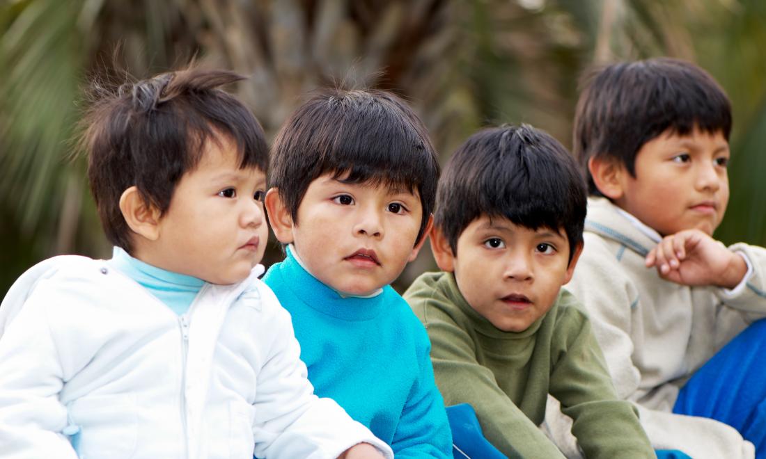 four young Latino brothers sitting in a row (toddler to elementary age)