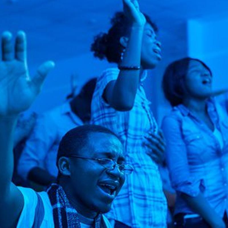 Young adults singing with hands raised