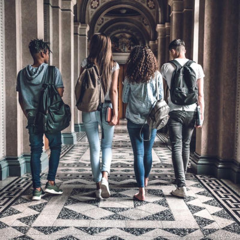 four university students walking through arch