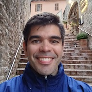 Photo of Dean Caso wearing a blue jacket in front of outdoor staircase