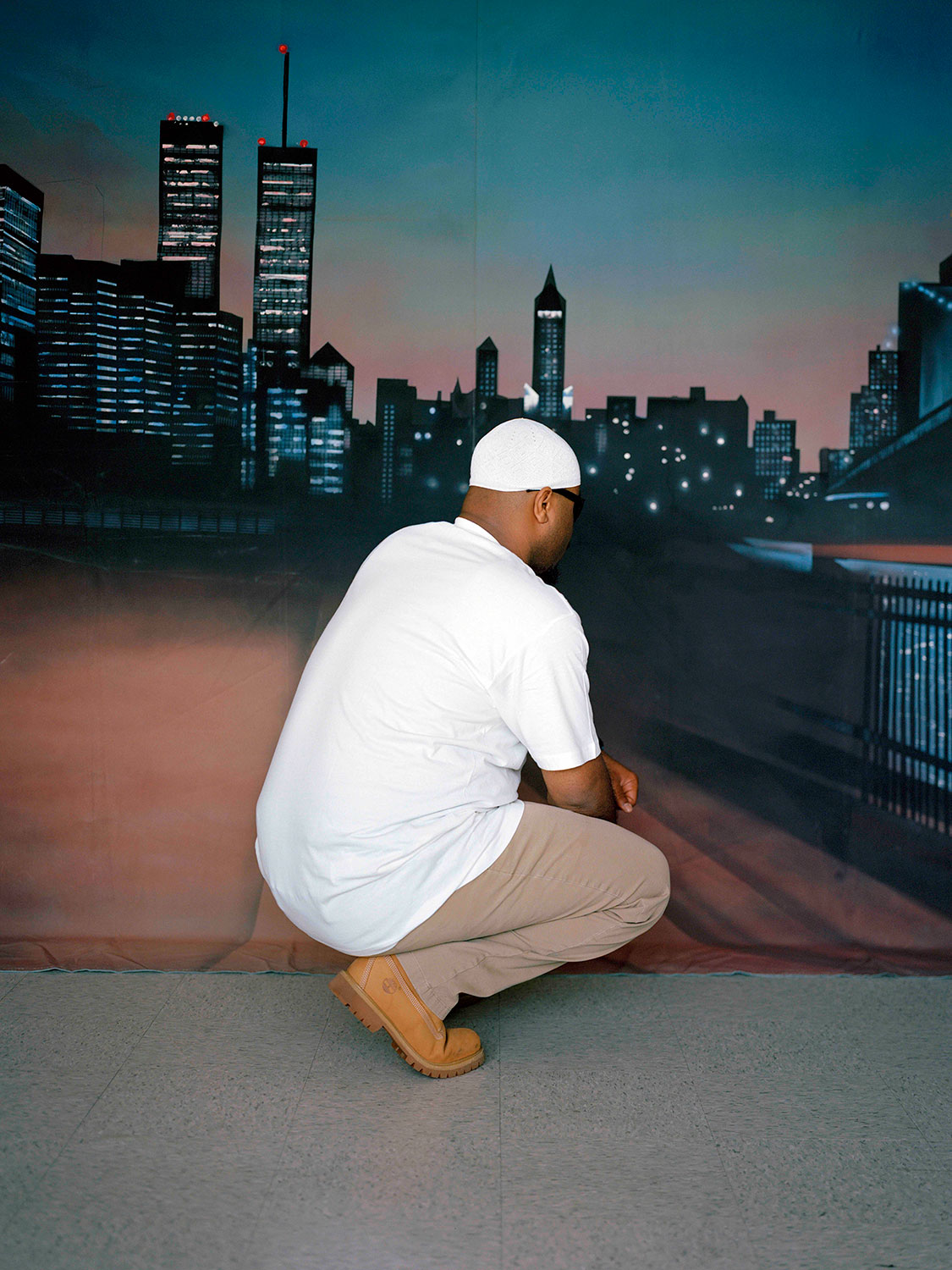 man wearing a jumpsuit facing an airbrushed cityscape