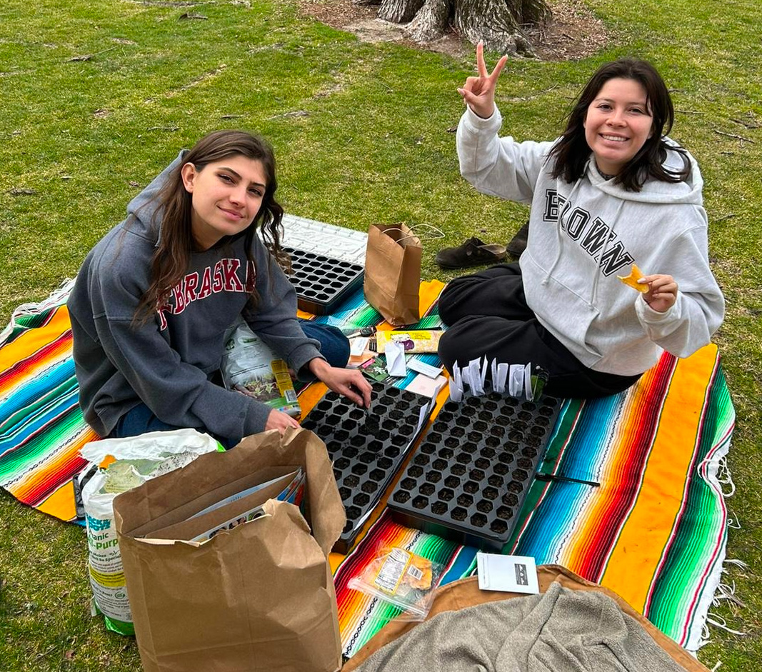 Clark and Hueston sit on a blanket outside, planting seeds