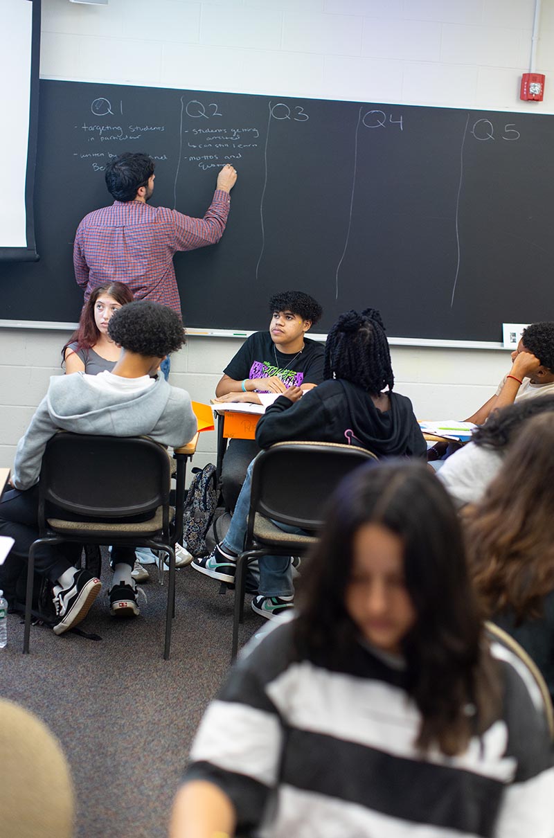 Brown graduate students writes on the chalkboard in an English class