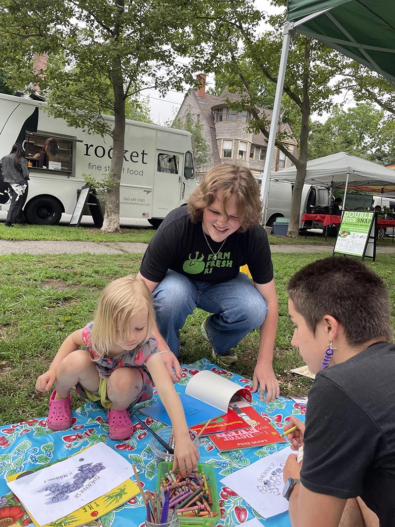 Brown student does art with children at farmers market