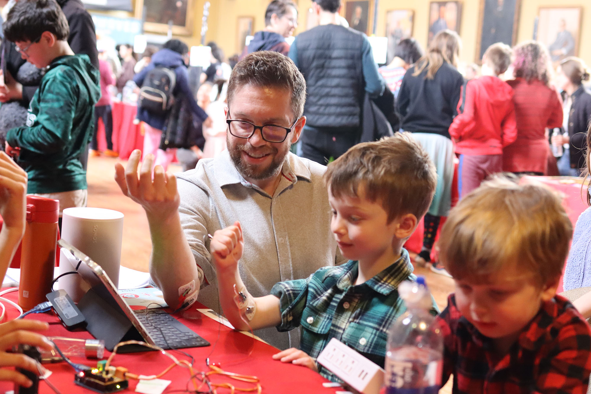 A parent and child try an exhibit together measuring electrical signals. 
