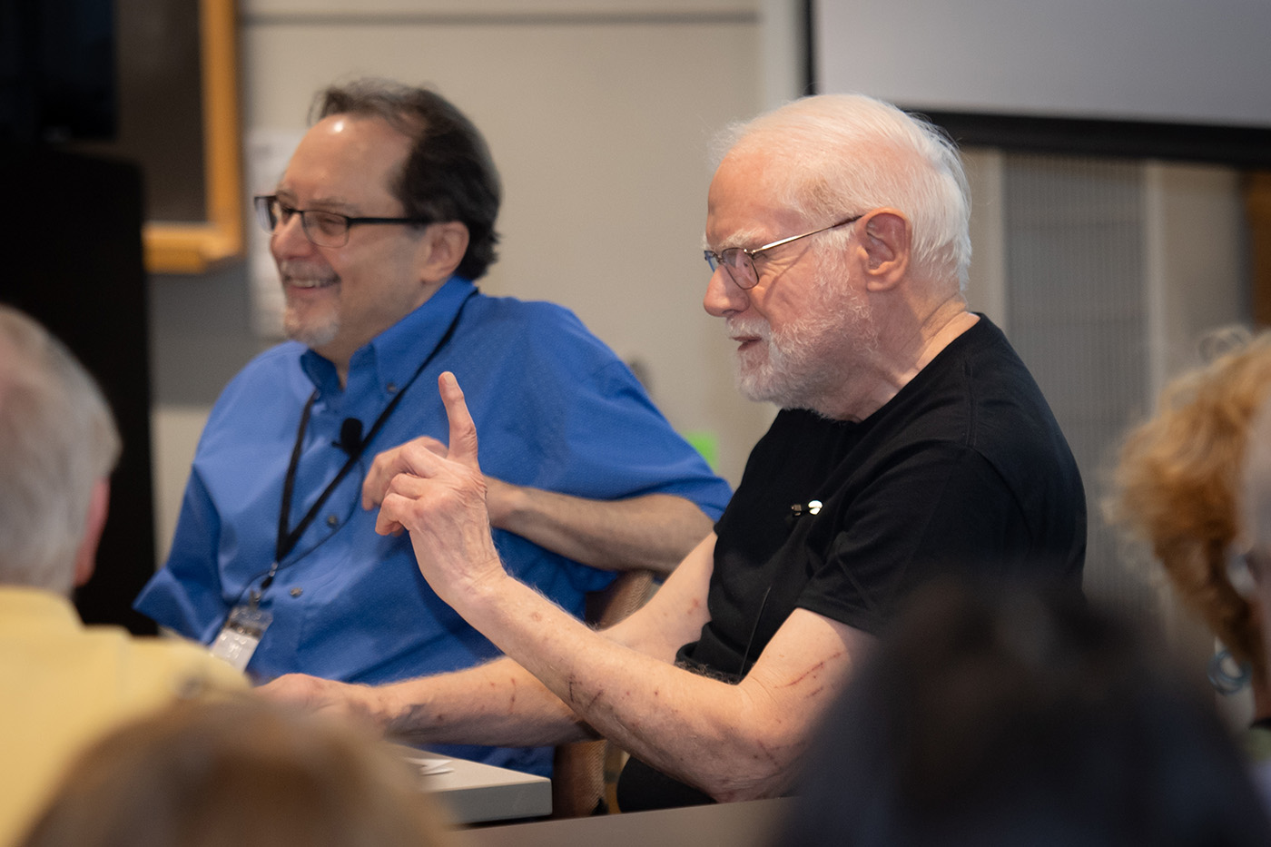 two people sitting behind a table and laughing