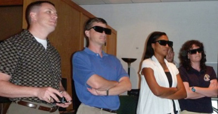 four people standing in a line with virtual reality glasses on