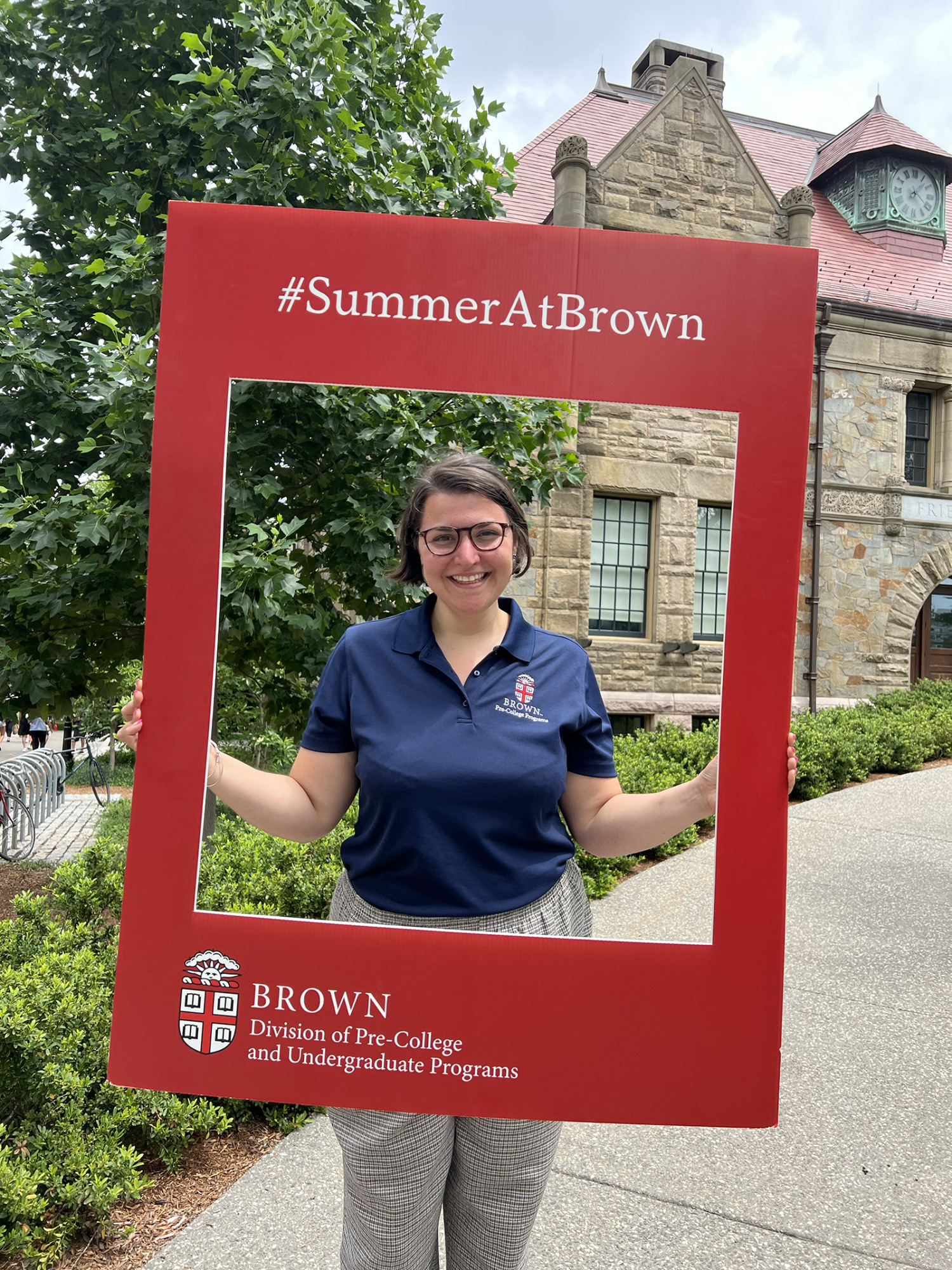 Brown staff member Olivia Mathis stops to pose behind a cardboard cutout "summer at brown"