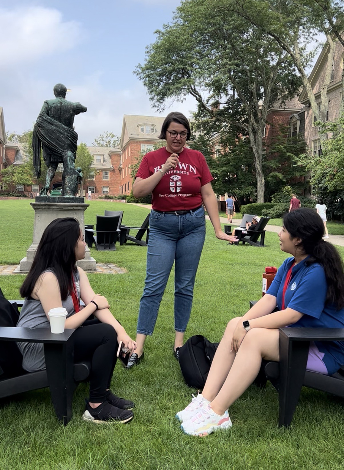 pre-college staff member Olivia Mathis stops to talk to students on the main green