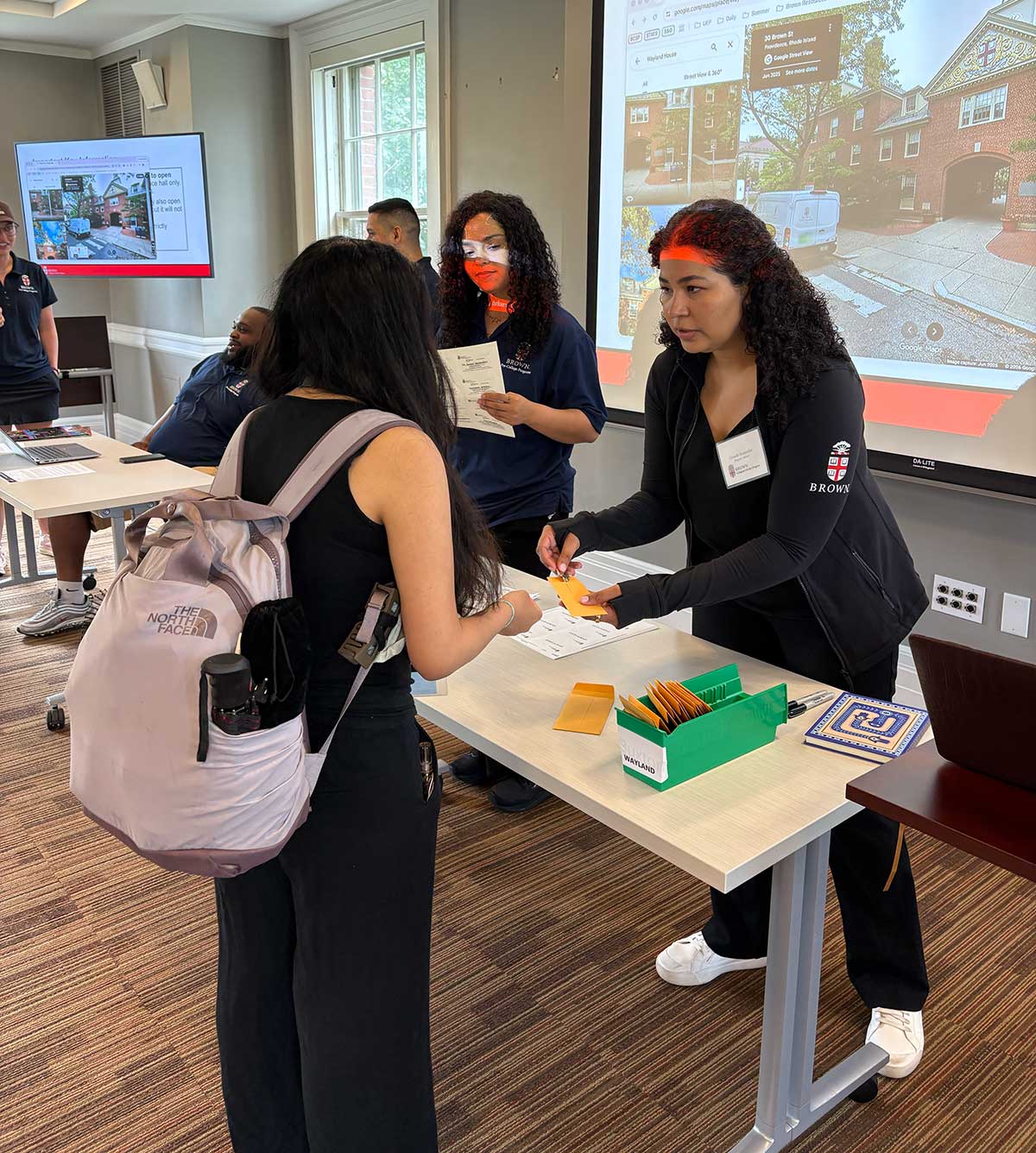 Brown staff welcome and check in students assiging them keys and maps as they begin to live on campus.