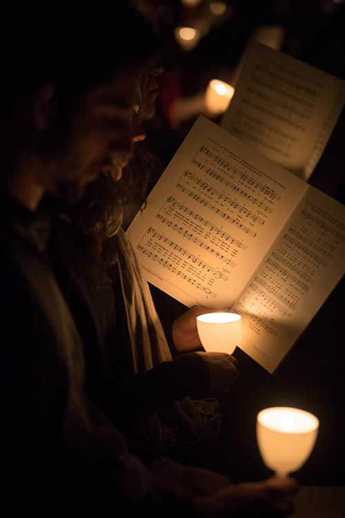Student holding sheet music lit only by candlelight