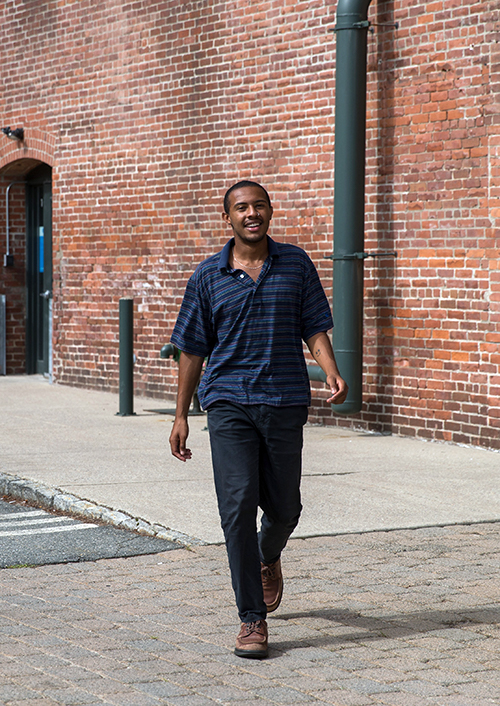 Aaron Cooper walking by a brick wall