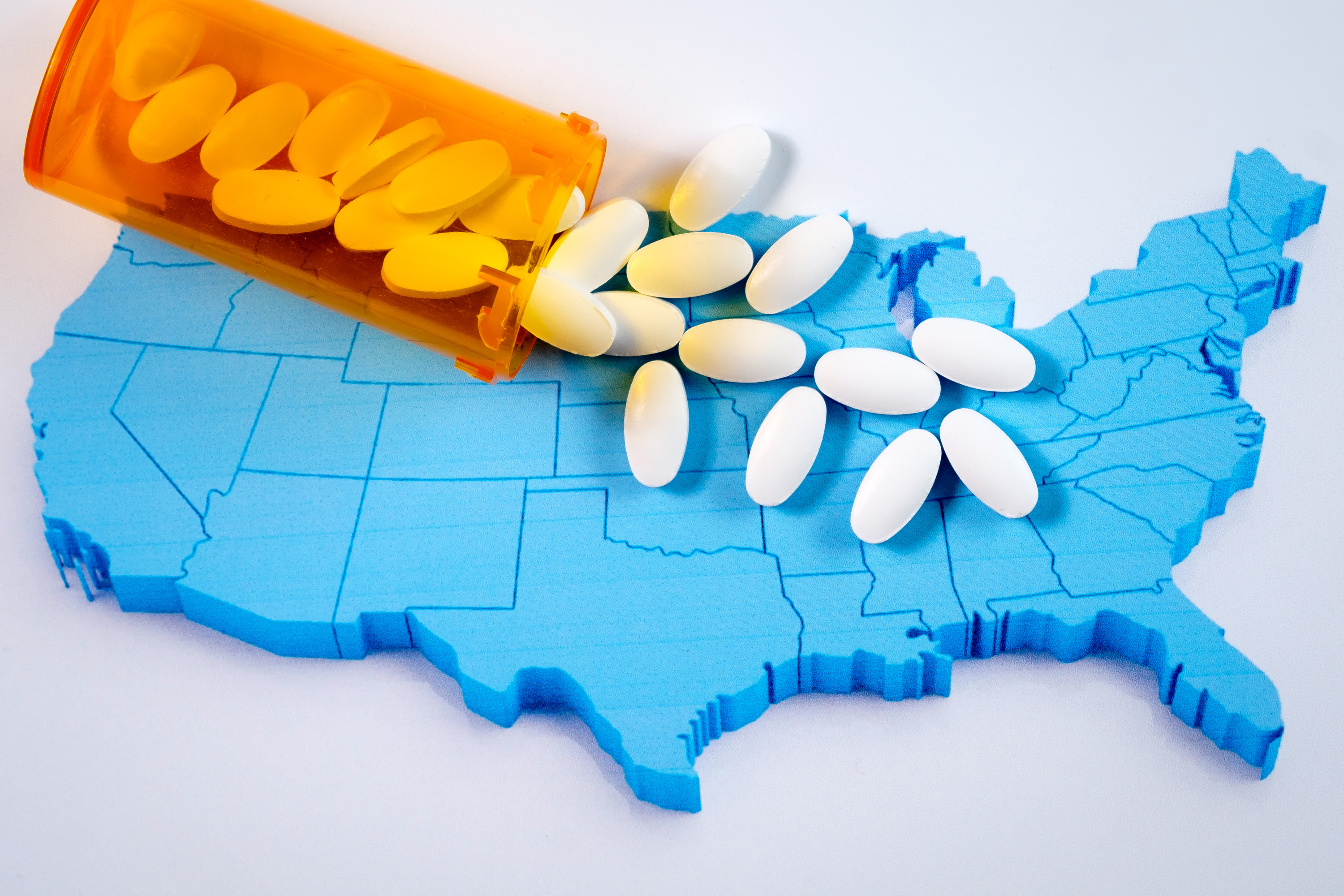 A bottle of pills poured over a map of the U.S.