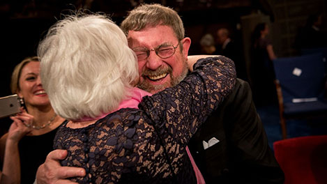 Kosterlitz hugging his wife during the Nobel ceremony