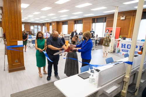 four people cutting a blue ribbon with large scissors
