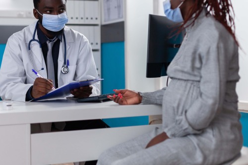 pregnant woman talking to doctor wearing mask