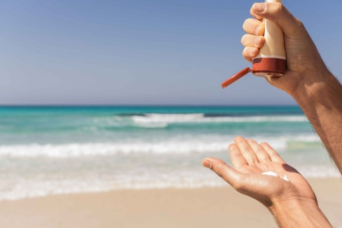 hands applying sunscreen at beach