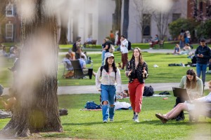 two students walk and talk on the busy College Green