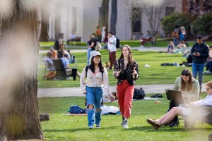 two students walk and talk on the busy College Green
