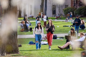 Two students walk and talk on the busy College Green