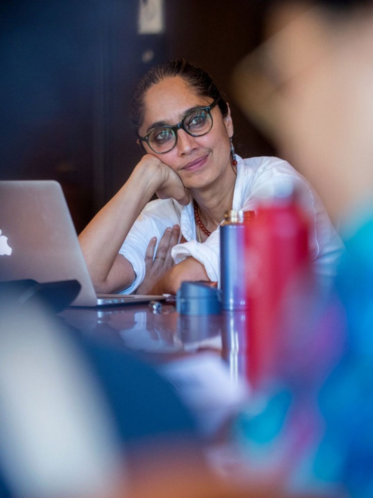 Leela Gandhi leaning on a table and smiling