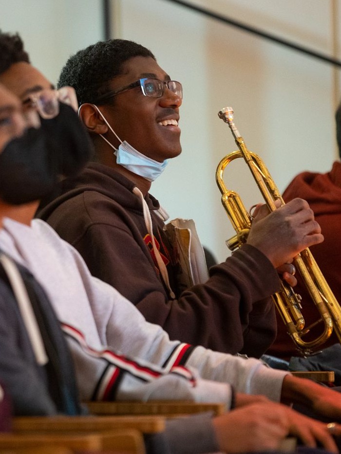 Derrick Pennix Jr. holding a trumpet and laughing