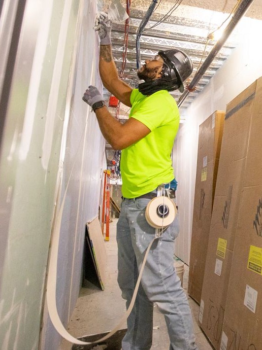 Andrew Ortiz taping a wall in a building under construction