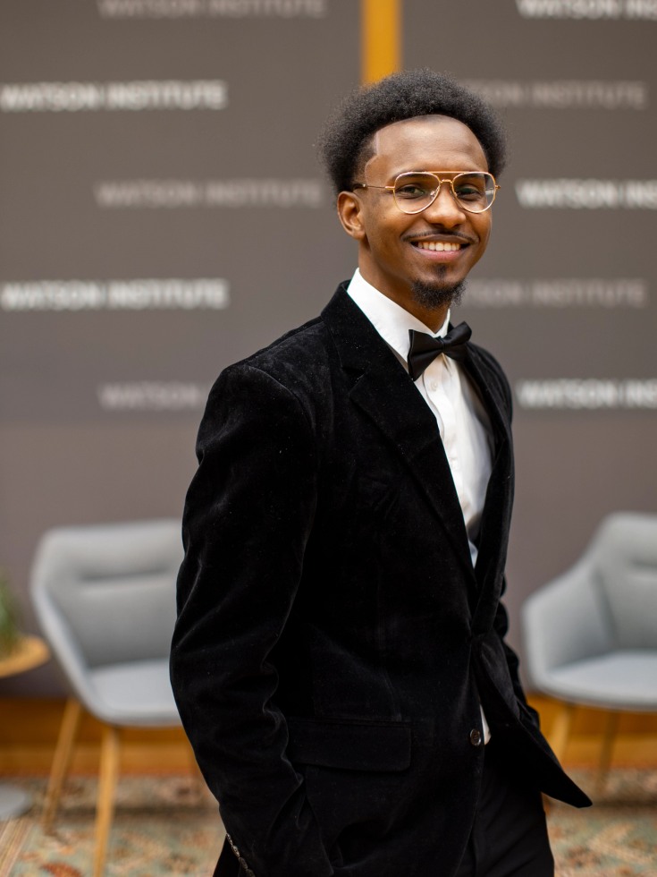 Hammi Sylla stands in a suit, smiling toward the camera