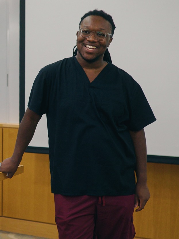 Jai Chavis stands at the front of a classroom, smiling