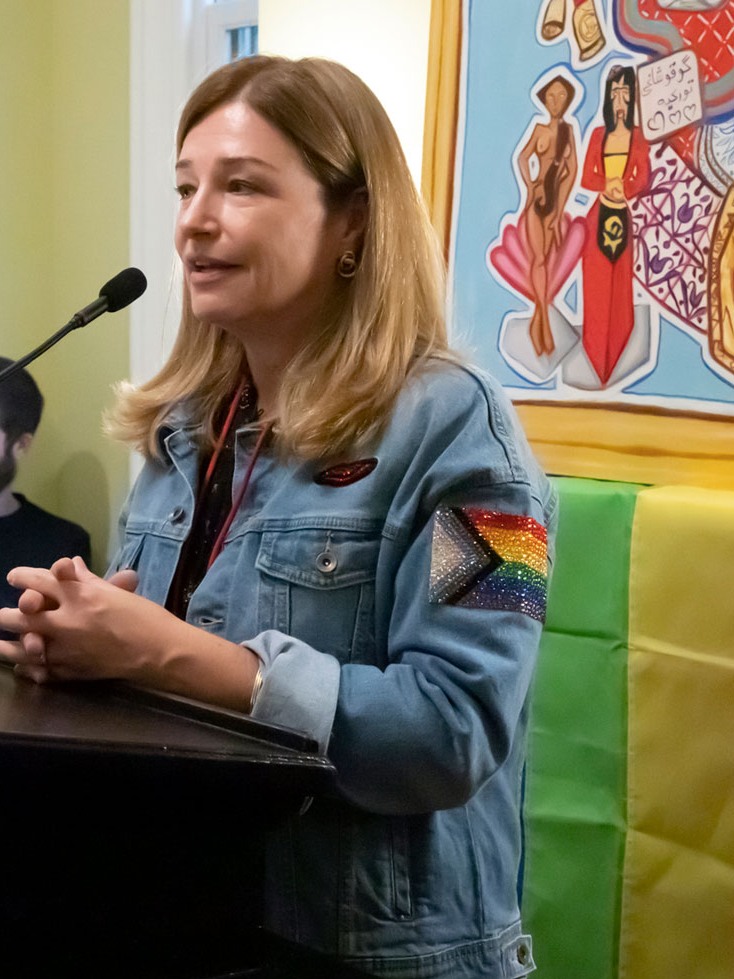 Donor Katie Gledhill speaks at a podium inside Stonewall House