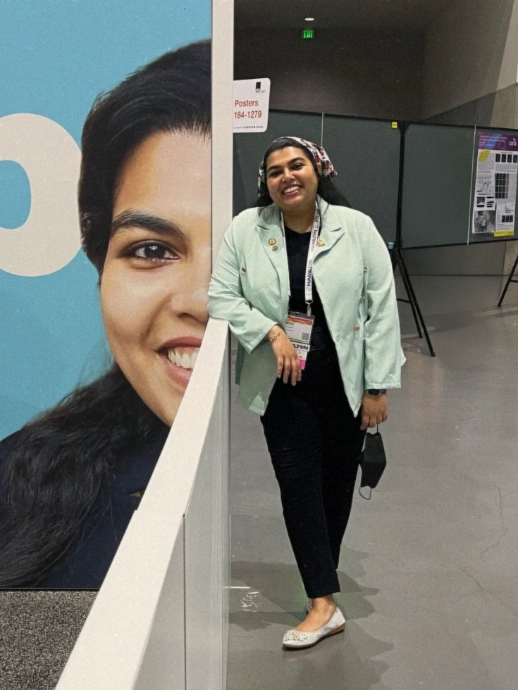 An image of Ramisa Fariha standing next to a large sign with her face on it.