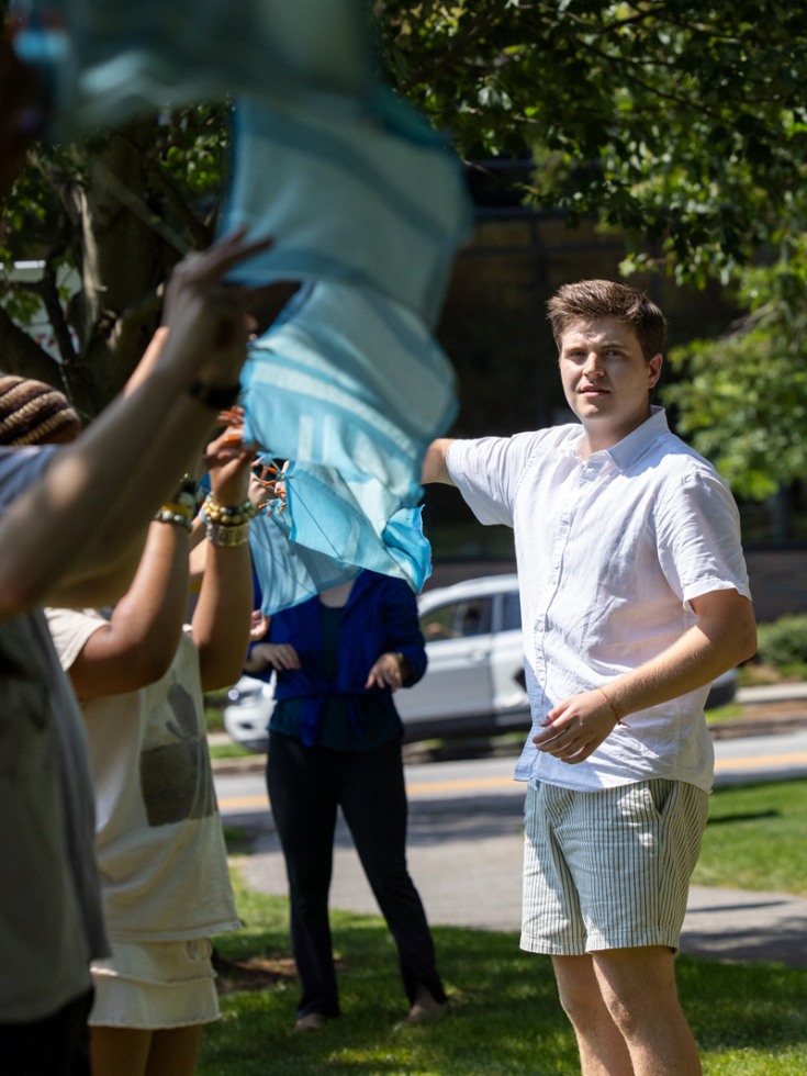 Logan Tullai helps volunteers hang the silk up to dry 