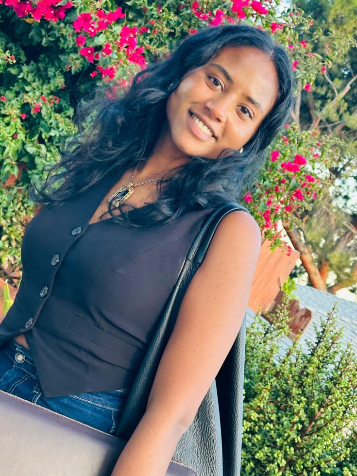 Maiya Jannah smiles in front of red flowers