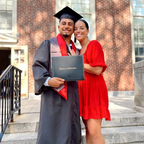 graduate holds up diploma next to family member