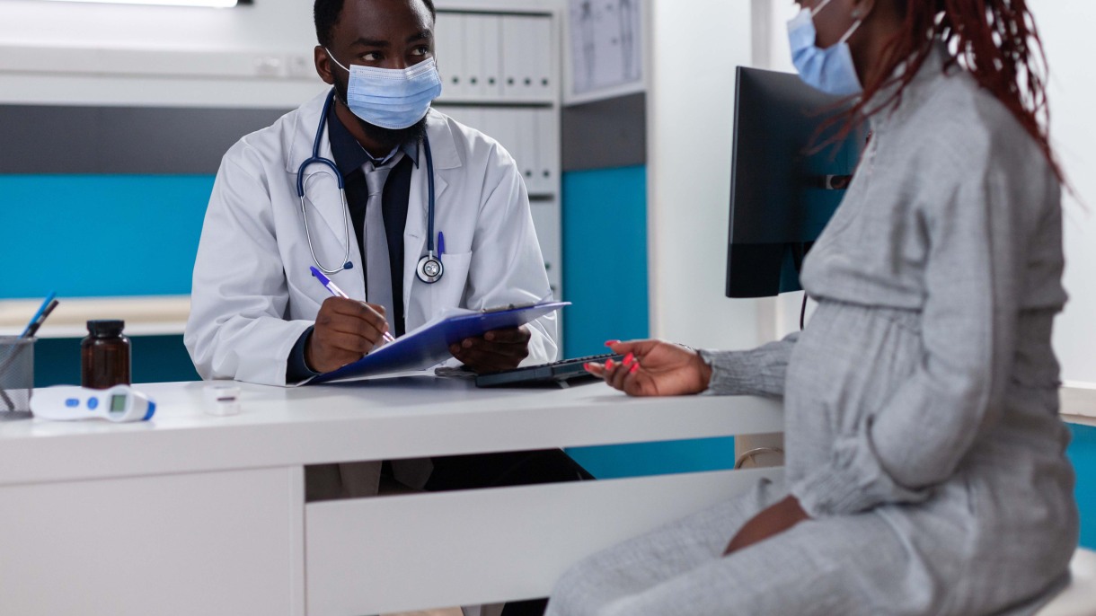 pregnant woman talking to doctor wearing mask