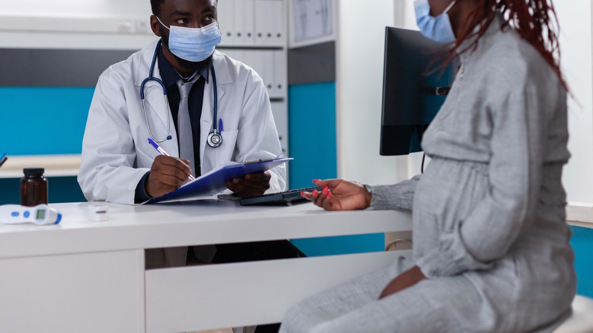 pregnant woman talking to doctor wearing mask