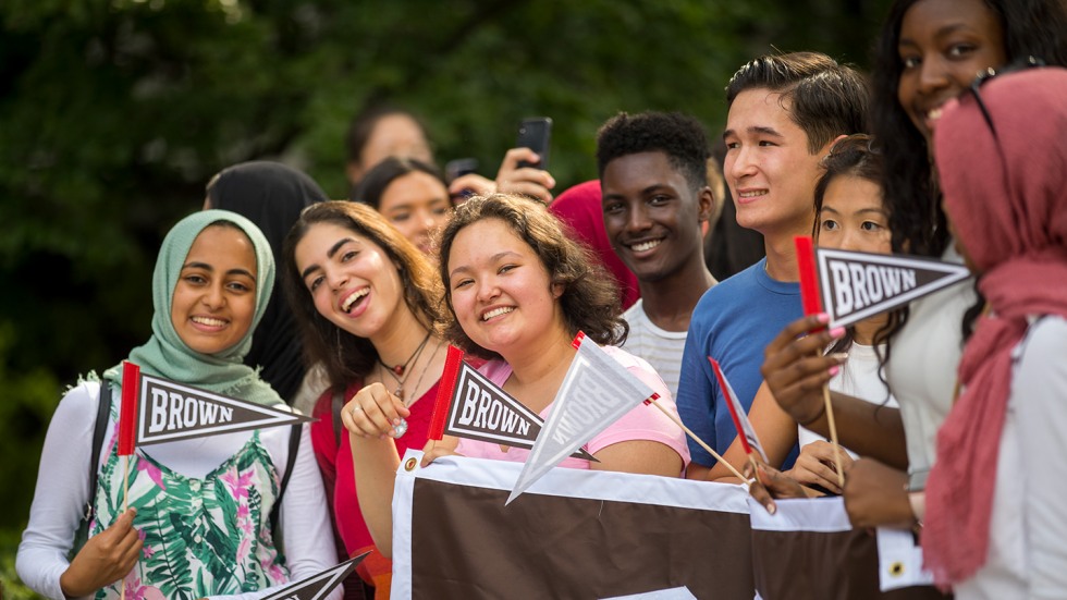 Students holding Brown banner and flags at convocation