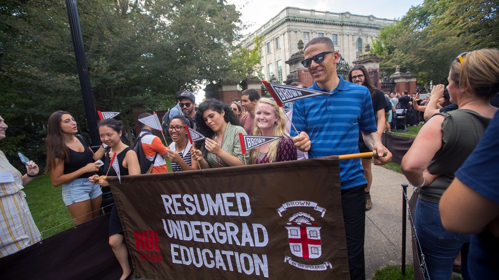 Processing students holding Resumed Undergrad Education banner