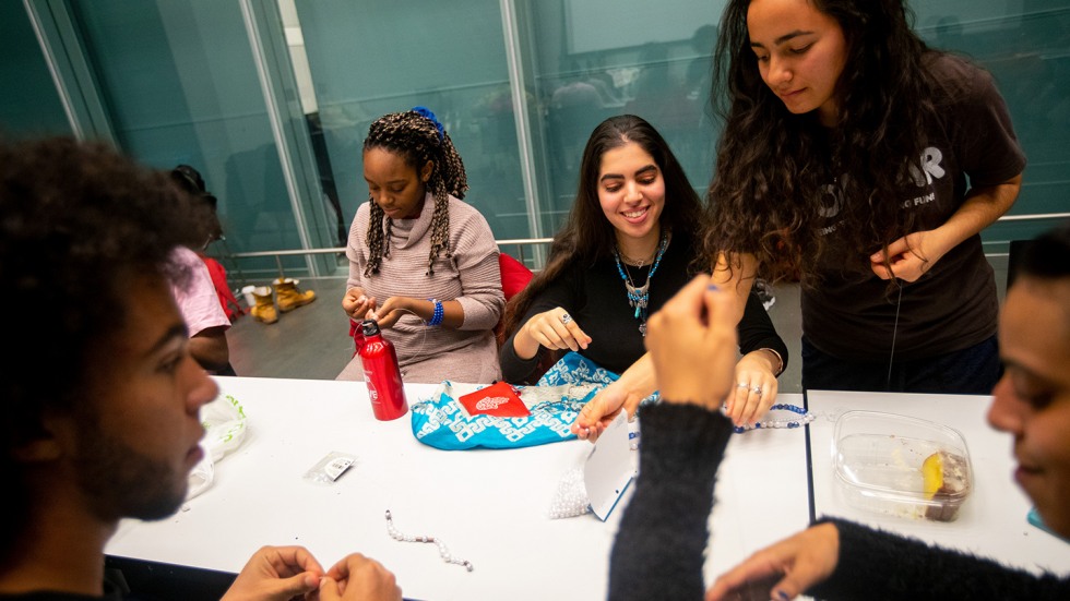 People at a table making beaded necklaces