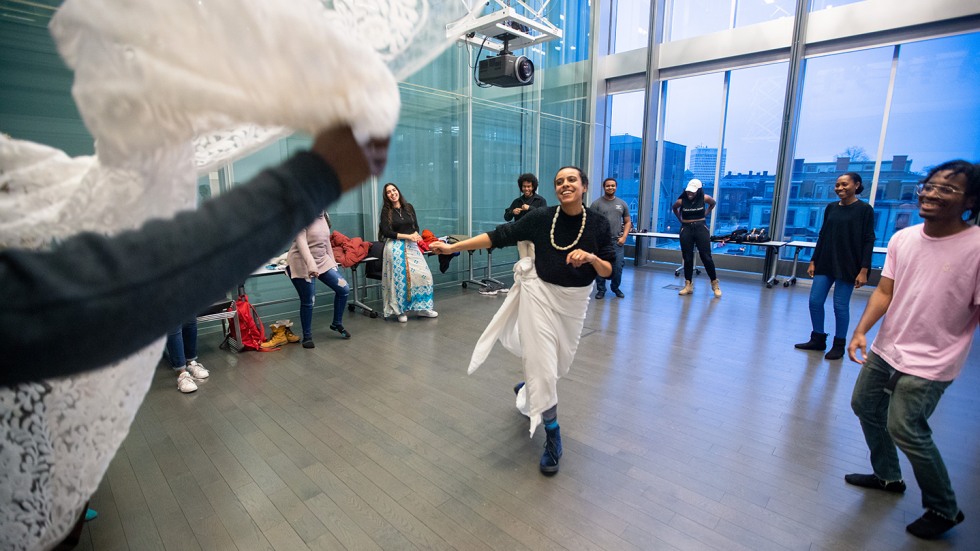 Woman in white skirt dancing in the center of a circle of people