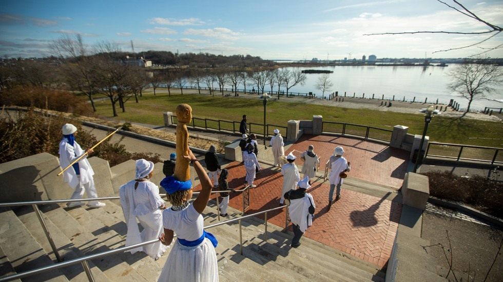 People dressed in white walking down steps toward water