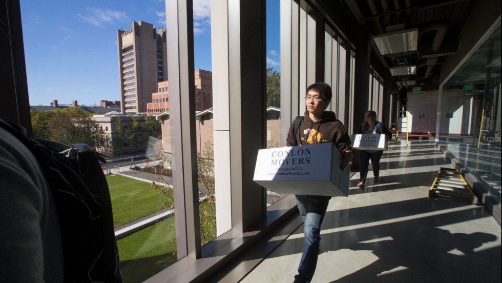 Qizhong Wang moving a box into the new building