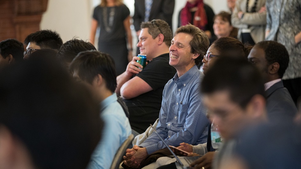 Jim Valles smiling, sitting among audience members